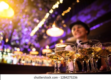 happy waitress holding a tray full of glasses or welcome drinks at an event