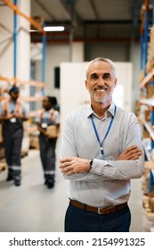 Happy Warehouse Foreman Standing With Arms Crossed At Industrial Storage Compartment And Looking At Camera.