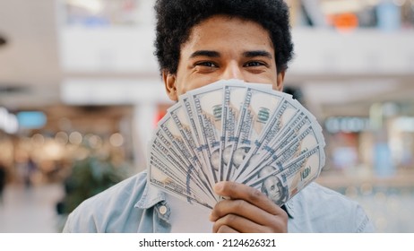 Happy wealthy successful smiling african american business man looking at camera holding fan of money hiding behind dollar banknotes showing financial profit winning salary savings loan credit cash - Shutterstock ID 2124626321