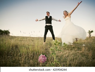 Happy wedding couple jumping for joy in beautiful scenery 