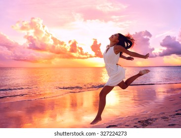 Happy Well Being Free Woman Jumping Of Happiness At Beach Sunset Enjoying Life In Serene Picturesque Sunset At The Ocean . Aspirational Happy Lifestyle With Pretty Young Asian Lady Enjoying Freedom.