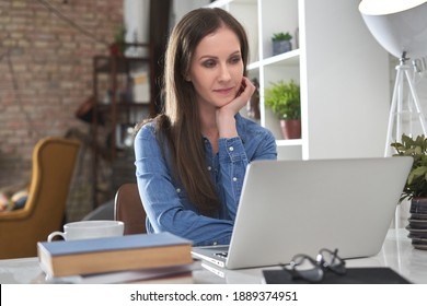 Happy White Business Woman Working At Home With Laptop Computer, Coffee, Books On Desk.