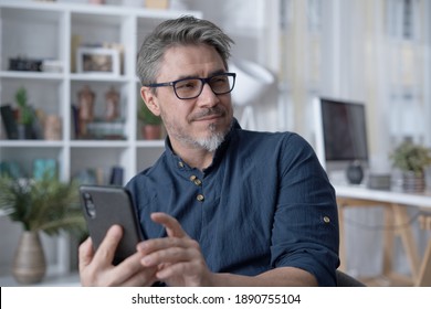 Happy White Older Man Using Phone, Talking On Video Chat At Home. Conference Call With Friend, Family Or Work. Reading Social Media.