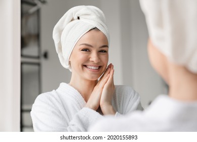 Happy White Woman With Toothy Smile Clean Young Clear Skin In Spa Bath Towel Looking At The Mirror. Beauty Treatment, Body And Hair Care. Girl After Taking Bath Shower At Home