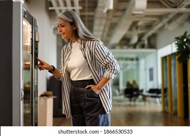 Happy white-haired mature woman using vending machine and smiling indoors - Shutterstock ID 1866530533