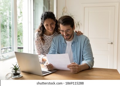 Happy Wife And Husband Wearing Glasses Reading Good News In Letter, Sitting At Table With Laptop, Checking Financial Documents, Received Mortgage Or Loan Approve Notification, Planning Budget