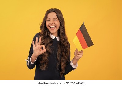 happy winking child hold german flag yellow background showing ok gesture, education abroad
