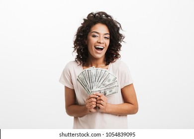 Happy Winner American Woman With Afro Hairstyle And Big Smile Holding Money Prize Dollar Cash Isolated Over White Background