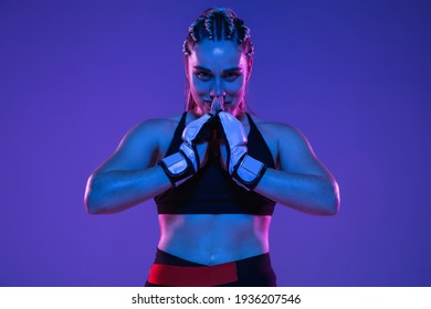 Happy winner. Portrait of young woman athletic female MMA fighter posing isolated on gradient blue-pink background in neon light. Concept of sport, competition, health. Copy space for ad. - Powered by Shutterstock