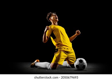 Happy winning pose. Young professional football player in yellow uniform isolated on black background. Sucessful match. Concept of action, team sport game, energy, vitality. Copy space for ad.