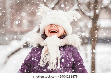 Happy Winter Children Holidays. Emotional Smiling Little Girl Child Having Fun Playing with Snowflakes in Winter Snow Park. Snow Falling in Winter Vacations. - Powered by Shutterstock