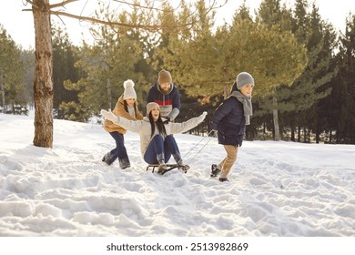 Happy winter family snow sledging mother in wintertime, playing during woodland nature adventure on Christmas, New Year active holiday fun outdoor, family fun ideas, spending vacation together outside