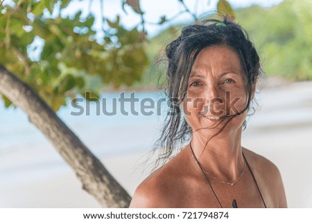 Happy woman in 40s relaxing on a tropical beach.