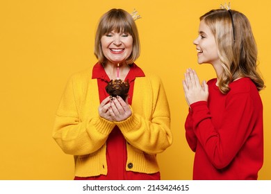 Happy Woman 50s In Red Shirt Crown Have Fun With Teenager Girl 12-13 Years Old Grandmother Granddaughter Hold Birthday Cake Blow Out Candle Isolated On Plain Yellow Background Family Lifestyle Concept