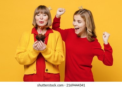 Happy Woman 50s In Red Shirt Crown With Teenager Girl 12-13 Years Old Grandmother Granddaughter Hold Birthday Cake Blow Out Candle Do Winner Gesture Isolated On Plain Yellow Background Family Concept