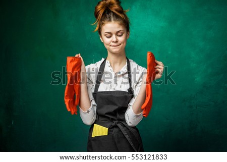 Happy woman after cleaning the house.Funny face.Holds red gloves in hands,hair in a bun.No problem tricky idea face expression.dressed in apron