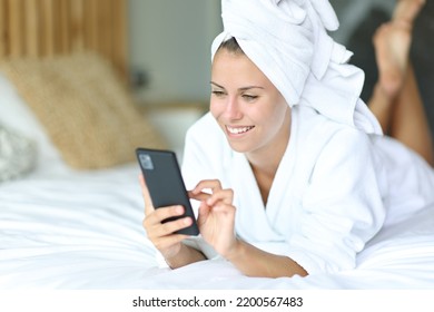 Happy woman after showering using mobile phone lying on the bed at home - Powered by Shutterstock