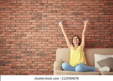 Happy Woman With Air Conditioner Remote At Home