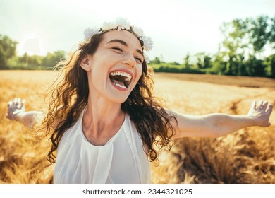 Happy woman with arms outstretched enjoying freedom in a wheat field - Joyful female breathing fresh air outside - Healthy life style, happiness and mental health concept
