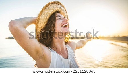 Happy woman with arms outstretched enjoying freedom at the beach - Joyful female having fun walking outside - Healthy lifestyle, happiness and mental health concept
