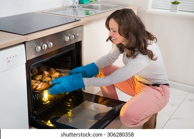 Happy Woman Baking Bread Roll In Kitchen Oven