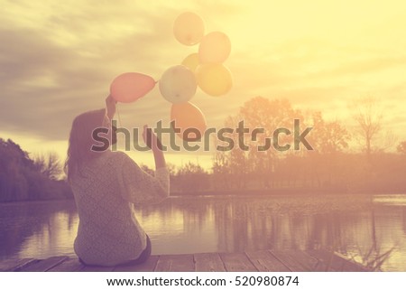 Happy woman with balloons in sunset