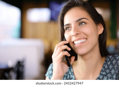 Happy woman in a bar interior talking on phone with perfect smile - Powered by Shutterstock