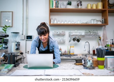 Happy Woman Barista Using Laptop For Take Order From Customer In Coffee Shop.