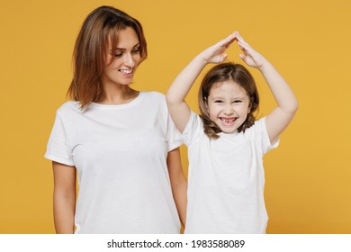 Happy Woman In Basic White T-shirt Have Fun With Child Baby Girl 5-6 Years Old Hold Folded Hands Above Head. Mom Little Kid Isolated On Yellow Color Background Studio. Mother's Day Love Family Concept