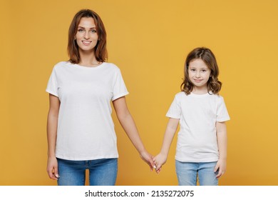 Happy Woman In Basic White T-shirt Have Fun With Child Baby Girl 5-6 Years Old Hold Hands. Mom Little Kid Daughter Isolated On Yellow Orange Color Background Studio. Mother's Day Love Family Concept