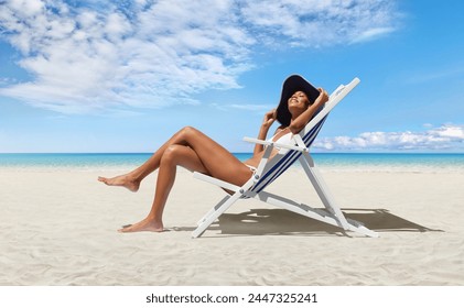 Happy woman at the beach on beach deck chair, sunbathing, wearing sun hat, in a sunny day with blue sky, concept a summer beach holiday, online shopping, booking travel, and resorts accommodations - Powered by Shutterstock