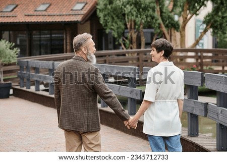 happy woman and bearded man holding hands, looking at each other, date, romance, elderly couple