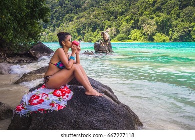 Happy Woman In Bikini Relaxing And Drinking Coffee On The Rock In Sea Beach, Andaman Sea, Mu Koh Surin National Park, Phangnga, Thailand