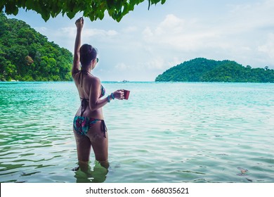 Happy Woman In Bikini Relaxing On Sea Beach Her Hand Holding Cup Of Coffee, Andaman Sea, Mu Koh Surin National Park, Phangnga, Thailand