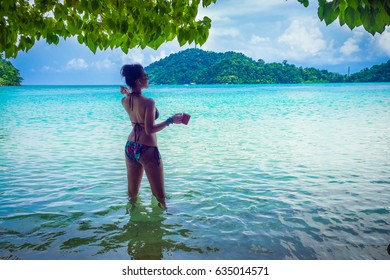 Happy Woman In Bikini Standing On Sea Beach Her Hand Holding Cup Of Coffee, Andaman Sea, Mu Koh Surin National Park, Phangnga, Thailand