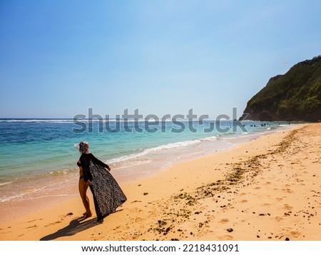 Happy woman in black bikini and sun hat at the beach