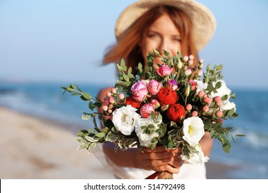 Happy Woman With Bouquet Of Flowers On Seashore