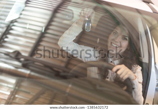Happy woman buyer examines her new vehicle in
car dealership