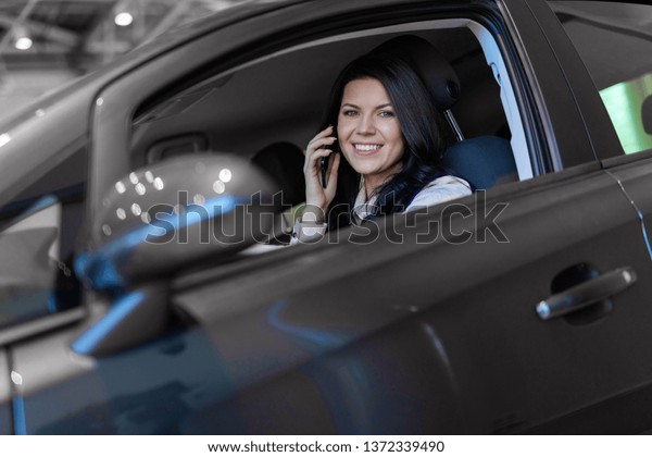 Happy woman buyer sitting in her new vehicle\
in car dealership