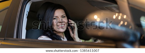 Happy woman buyer sitting in her new vehicle\
in car dealership