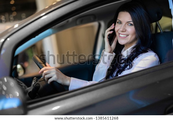 Happy woman buyer sitting in her new vehicle
in car dealership