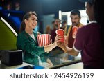 Happy woman buying soda and popcorn before movie projection in cinema. 