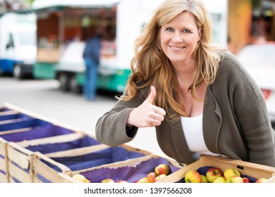 
Happy Woman Buys Apples At The Farmers Market