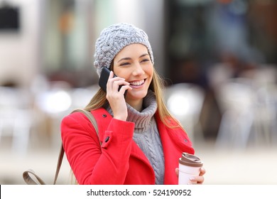 Happy Woman Calling On The Mobile Phone And Holding A Take Away Coffee In The Street In Winter