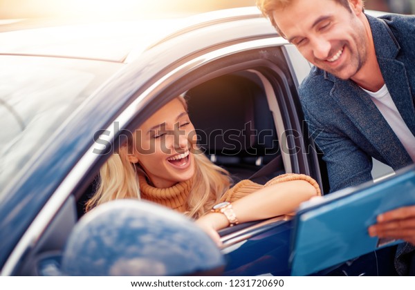 Happy woman with car\
dealer in auto salon.