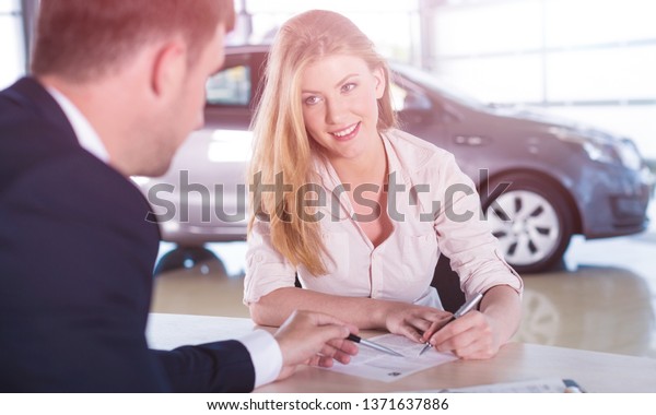 Happy woman\
with car dealer in auto show or\
salon