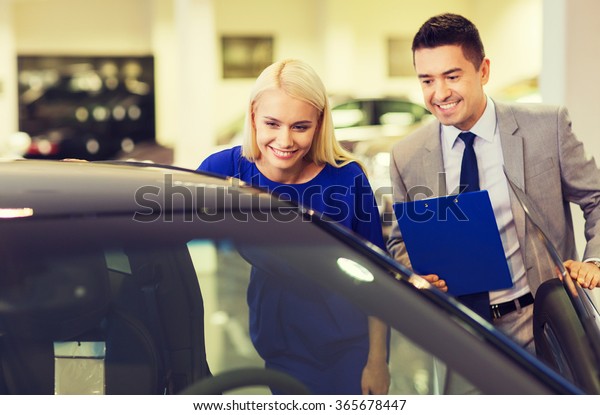 happy woman\
with car dealer in auto show or\
salon