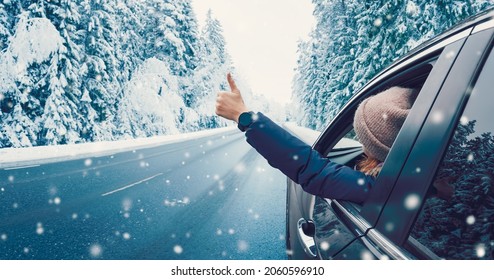 Happy woman in the car gesture finger up on the snowy background. - Powered by Shutterstock