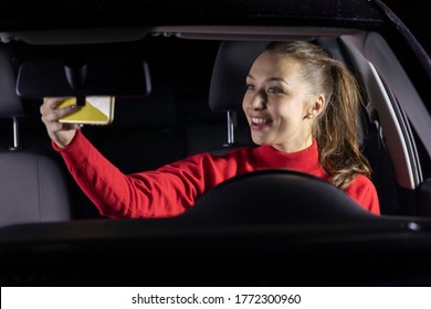 Happy Woman In Car At Night Stopped Parked And Makes Video Calls To Family. Smiling Female Driver Sitting Inside Car Makes Selfie. Concept: Safe Journey, Mobile And Internet Connection With Relatives