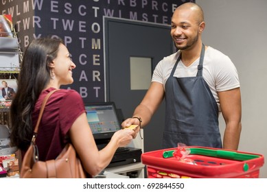 Happy Woman At Checkout Of Grocery Store Paying With Credit Card To Cashier. Smiling Woman Paying With Her EC Card At Supermarket. Mature Woman At Cash Register Paying With Credit Card To Man.